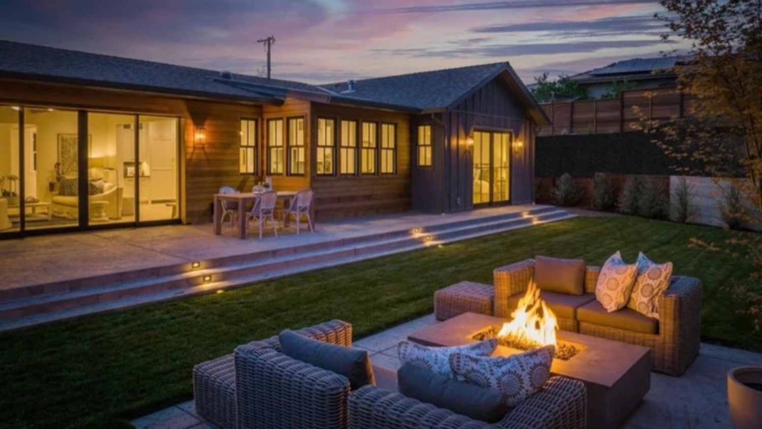 The exterior of a large house with an outdoor fireplace and outdoor lighting