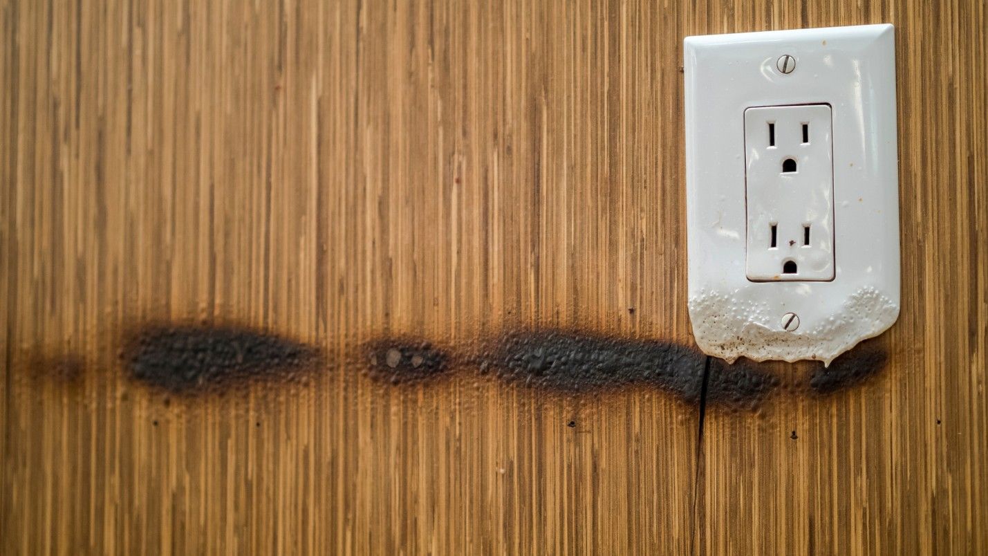 An electrical outlet with signs of burning, indicating electrical emergency.