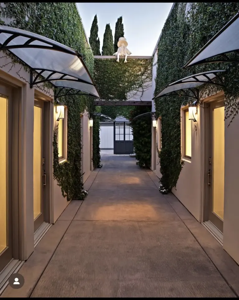 Ivy-covered courtyard walkway with wall sconces at dusk