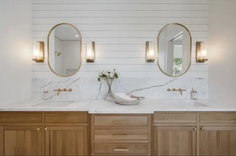 Bathroom double vanity with brass sconces and oval mirrors